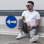 "Immer in Richtung Lachen" Mann hockt am Boden heben Wegschild