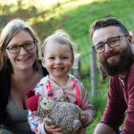 Mutter, Vater und Kind lachen in die Kamera